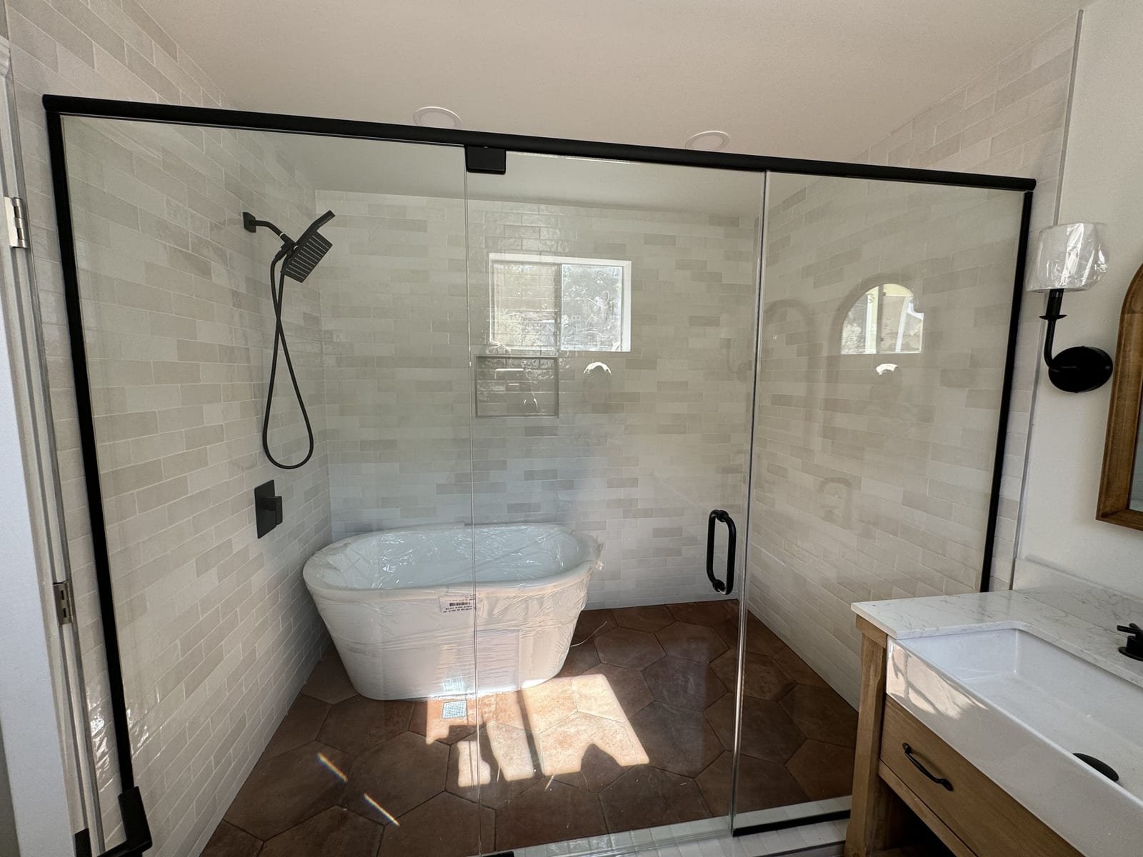 Finished bathroom with a freestanding tub and glass enclosure